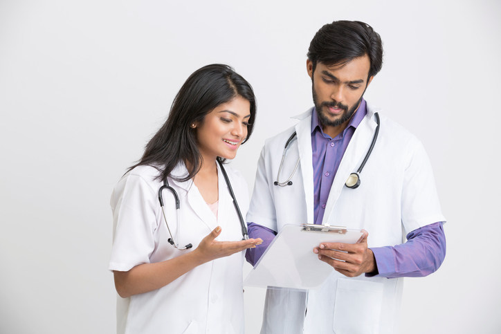 Examining two young Indian attractive doctors Two young Indian attractive doctors on white background